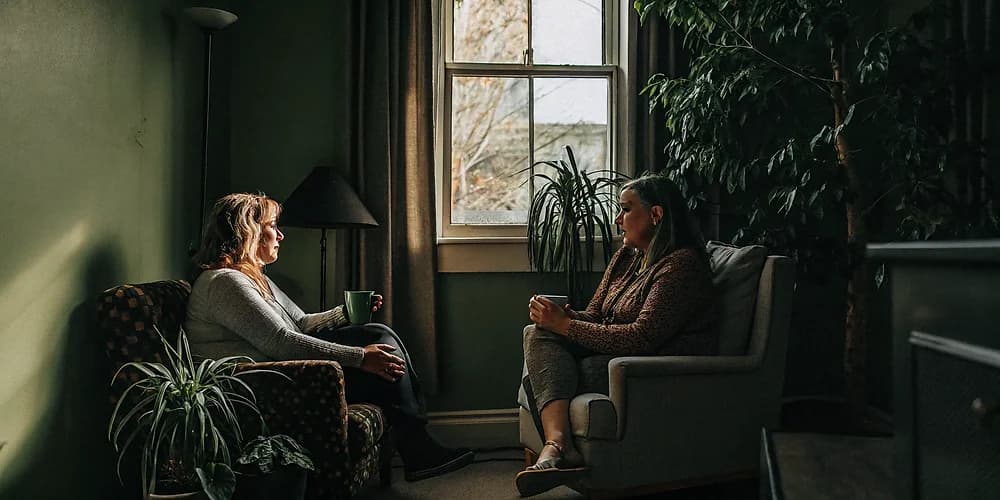 Warm counselling office in Edmonton with therapist and client in conversation, soft natural light, calm atmosphere